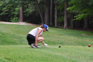 woman sets golf ball on tee
