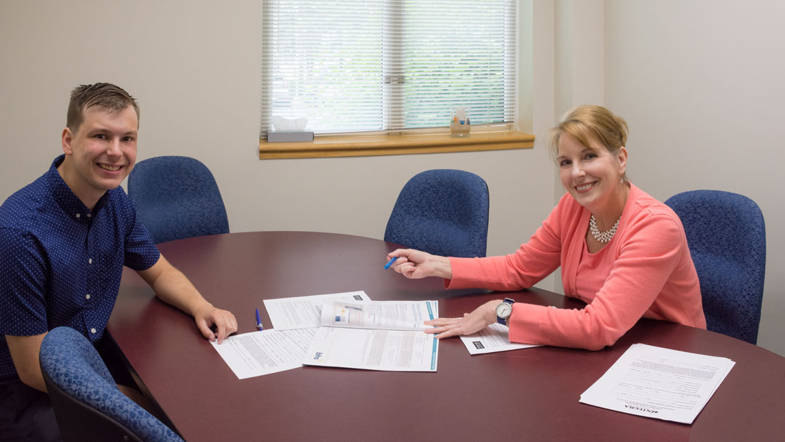 Student and instructor at a desk with pen and paper