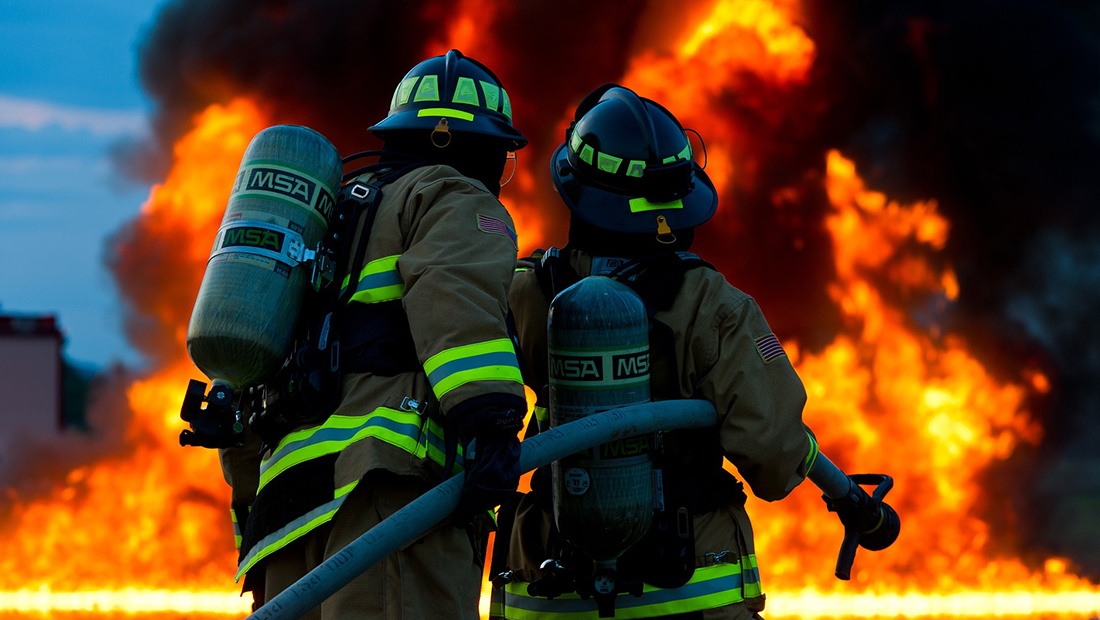 Two firefighters carrying a hose